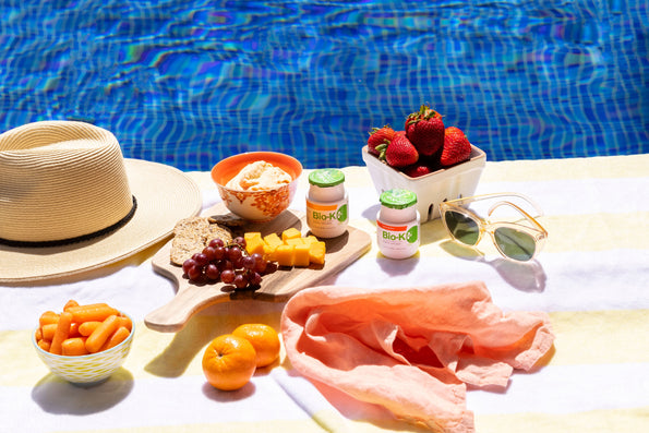 Fruits, snacks and Bio-K+ bottle near a swimming pool