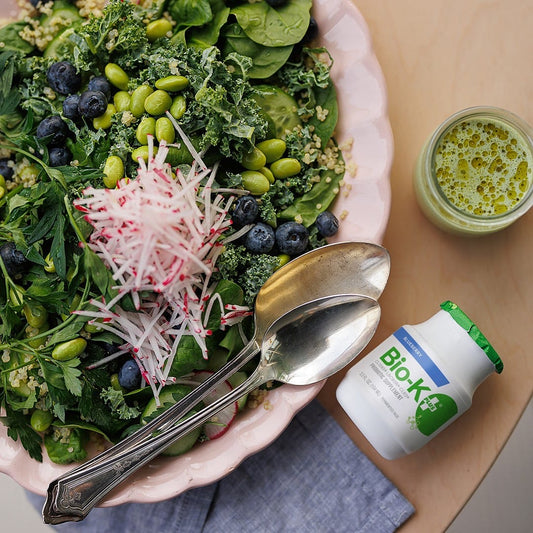 Bio-K+ Blueberry probiotic beside a kale quinoa salad with edamame and blueberries.