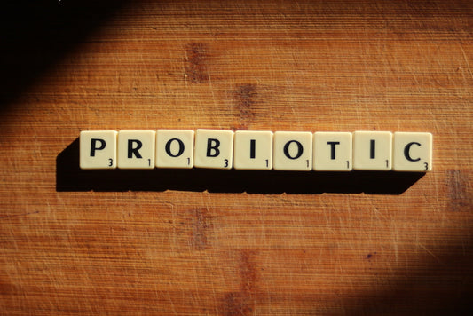 Probiotic spelled out in Scrabble letter tiles on a wooden cutting board
