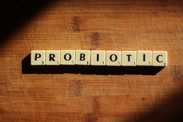Probiotic spelled out in Scrabble letter tiles on a wooden cutting board