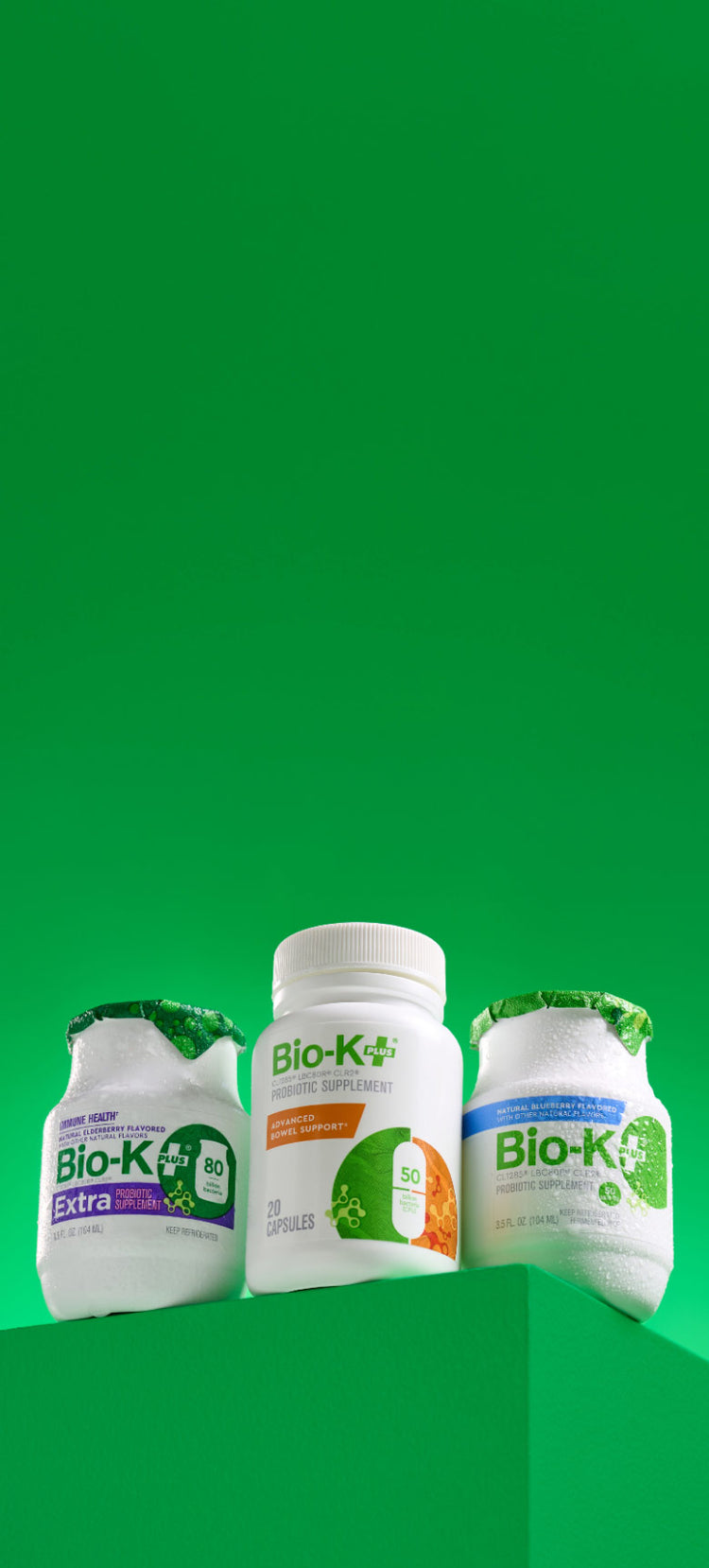 Three Bio-K+ supplement bottles on a green background